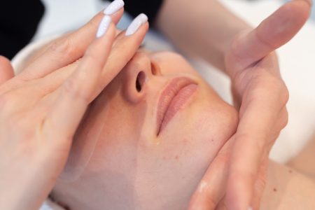 zbliżenie na twarz kobiety w trakcie masażu w salonie kosmetycznym